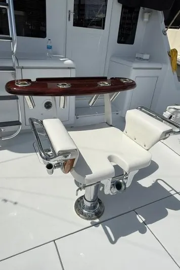  Yacht Photos Pics Fishing chair on 2002 Hatteras 55 Convertible yacht deck, featuring rod holders and white upholstery.