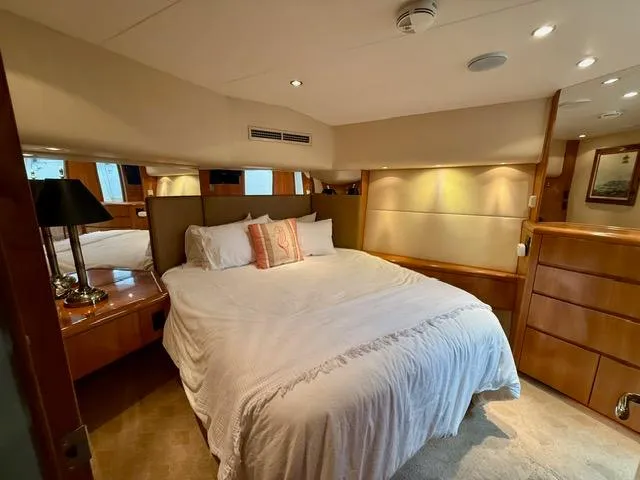  Yacht Photos Pics Luxurious bedroom interior of 2002 Hatteras 55 Convertible yacht with elegant wood finishes.
