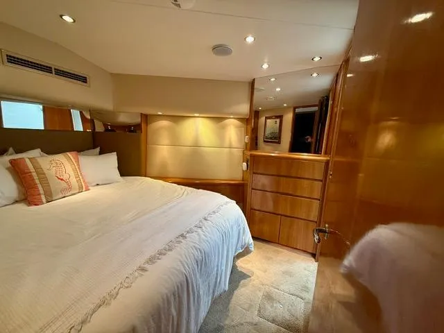  Yacht Photos Pics Luxurious bedroom interior of 2002 Hatteras 55 Convertible yacht with elegant wood finishes.