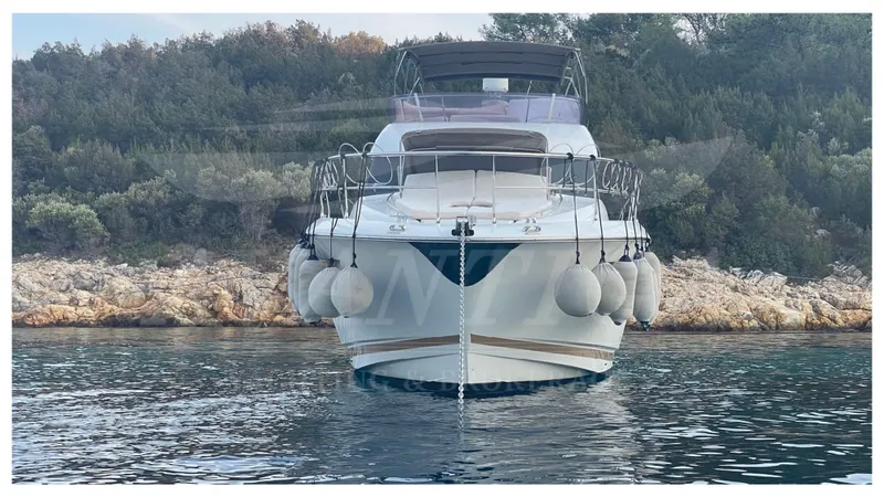 Yacht Photos Pics Front view of a 2012 Prestige 500 yacht anchored near a rocky shoreline.