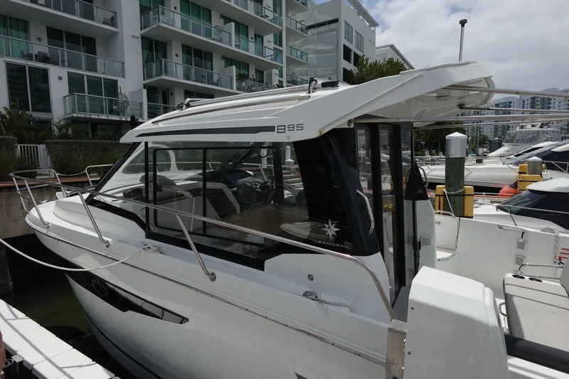  Yacht Photos Pics 2021 Jeanneau NC 895 boat docked near modern apartments.