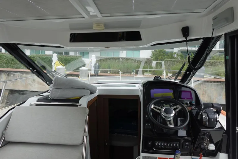  Yacht Photos Pics Interior view of 2021 Jeanneau NC 895 boat cockpit with steering wheel and navigation equipment.