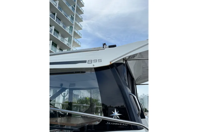  Yacht Photos Pics 2021 Jeanneau NC 895 boat docked near modern building, showcasing sleek design.