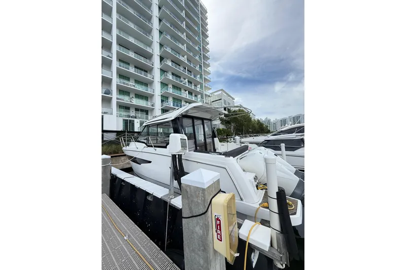  Yacht Photos Pics 2021 Jeanneau NC 895 docked near modern high-rise buildings.