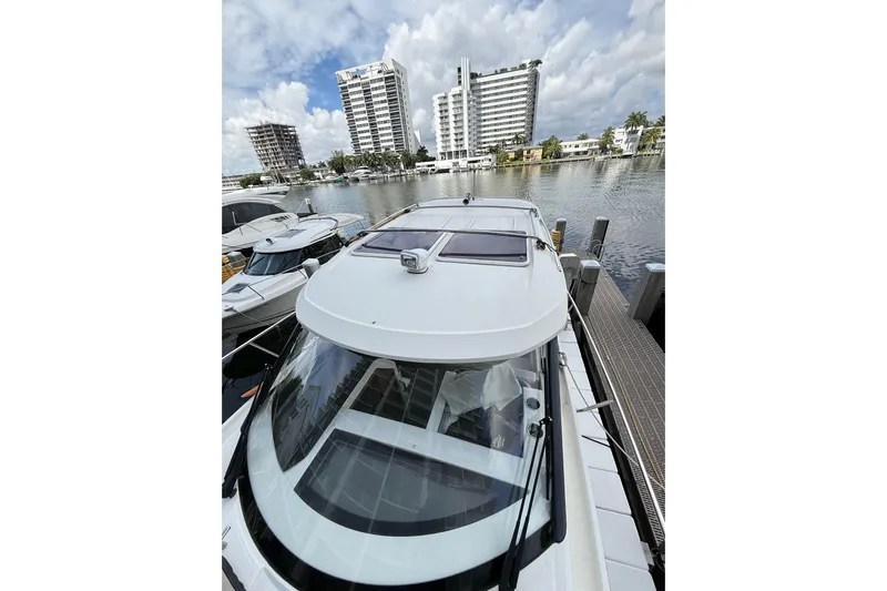  Yacht Photos Pics 2021 Jeanneau NC 895 docked near modern waterfront buildings under a cloudy sky.