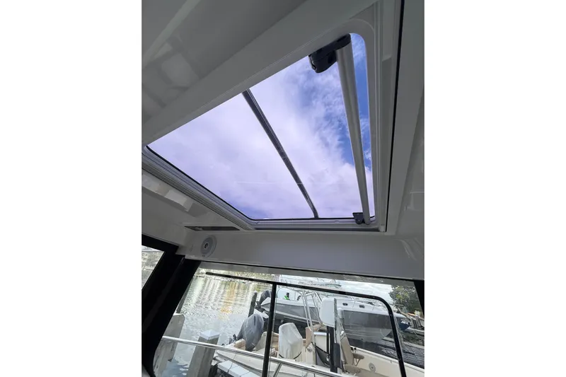  Yacht Photos Pics 2021 Jeanneau NC 895 boat interior with open sunroof and view of sky.