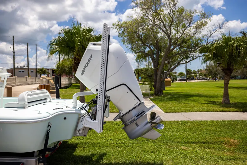  Yacht Photos Pics 2024 Yellowfin 24 CE boat with Mercury outboard motor, parked on grass under a cloudy sky.