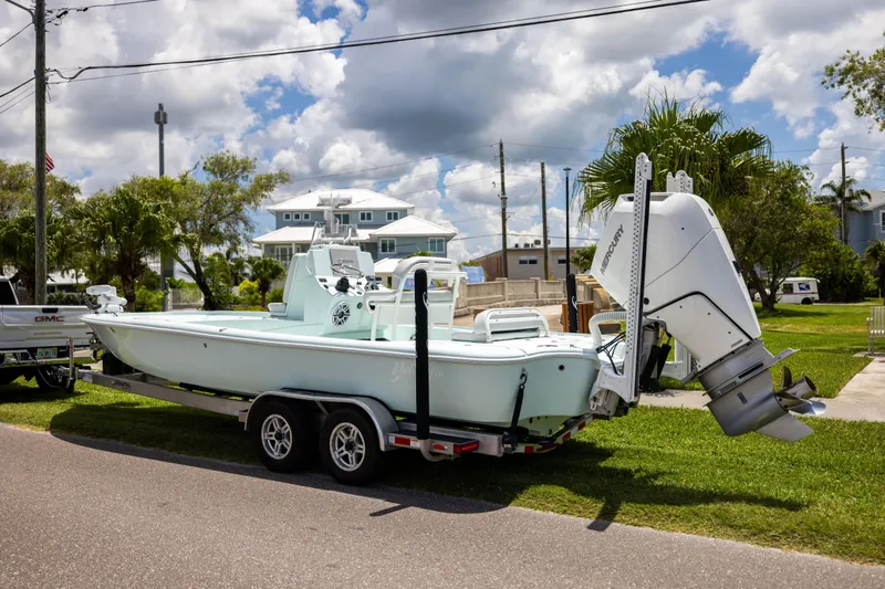  Yacht Photos Pics 2024 Yellowfin 24 CE boat on trailer, parked outdoors under cloudy sky.