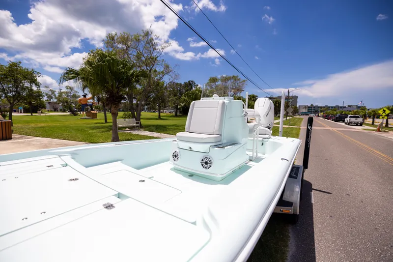  Yacht Photos Pics 2024 Yellowfin 24 CE boat on trailer, parked near a grassy area under a clear sky.