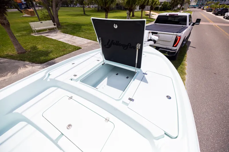  Yacht Photos Pics 2024 Yellowfin 24 CE boat on trailer, open storage compartment, parked near a road.