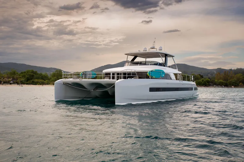 Mahe III Yacht Photos Pics 2023 Lagoon SIXTY 7 yacht on serene water with scenic background.