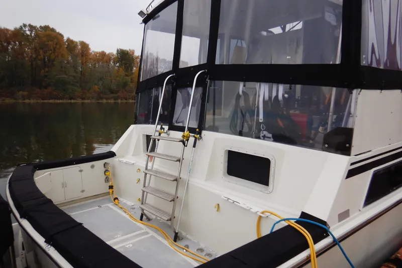 Alaska Sea Duction Yacht Photos Pics 1988 Camargue 48 Cockpit Motor Yacht with ladder and cables, docked by autumn trees.