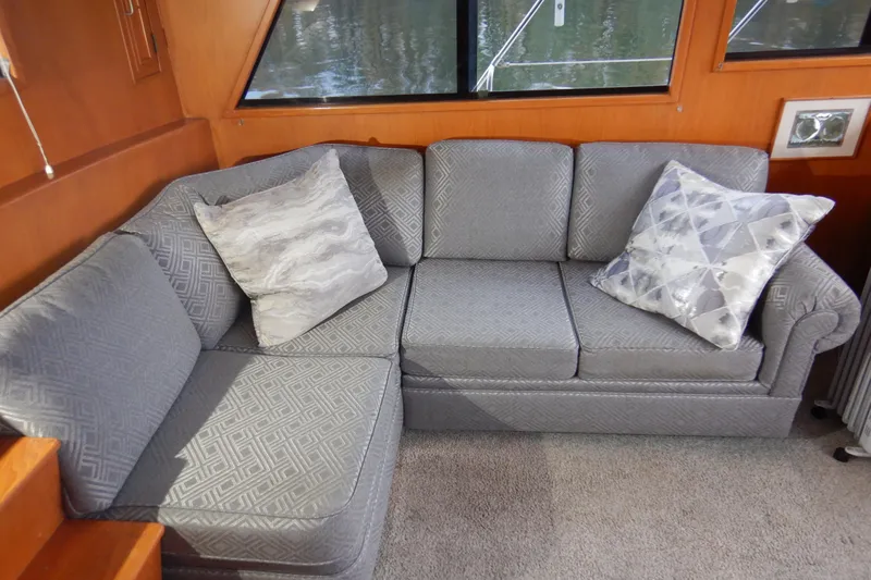 Alaska Sea Duction Yacht Photos Pics Gray sofa with patterned cushions inside a 1988 Camargue 48 Cockpit Motor Yacht.
