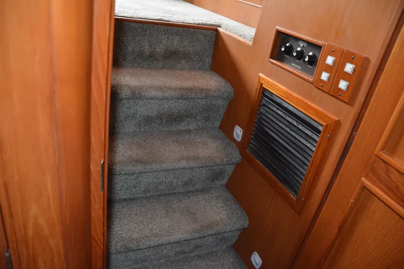 Alaska Sea Duction Yacht Photos Pics Carpeted stairs inside 1988 Camargue 48 Cockpit Motor Yacht with wooden paneling and control switches.