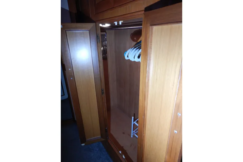 Alaska Sea Duction Yacht Photos Pics Wooden closet interior on 1988 Camargue 48 Cockpit Motor Yacht, featuring hangers and storage space.