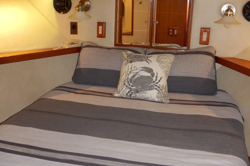 Alaska Sea Duction Yacht Photos Pics Cozy bedroom interior of 1988 Camargue 48 Cockpit Motor Yacht with striped bedding and decorative pillow.