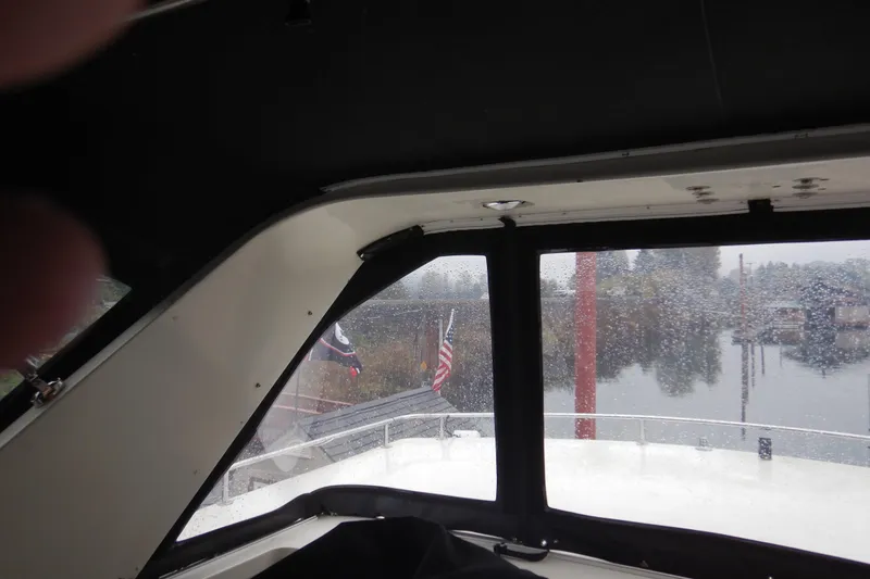 Alaska Sea Duction Yacht Photos Pics Interior view of 1988 Camargue 48 Cockpit Motor Yacht with rainy window and flags.