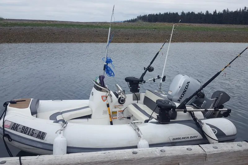 Alaska Sea Duction Yacht Photos Pics A small fishing boat with Honda motor and fishing rods docked by the shore.