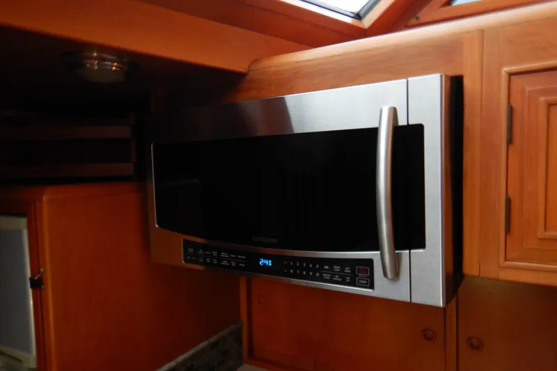 Alaska Sea Duction Yacht Photos Pics Microwave in 1988 Camargue 48 Cockpit Motor Yacht kitchen, featuring wooden cabinetry.