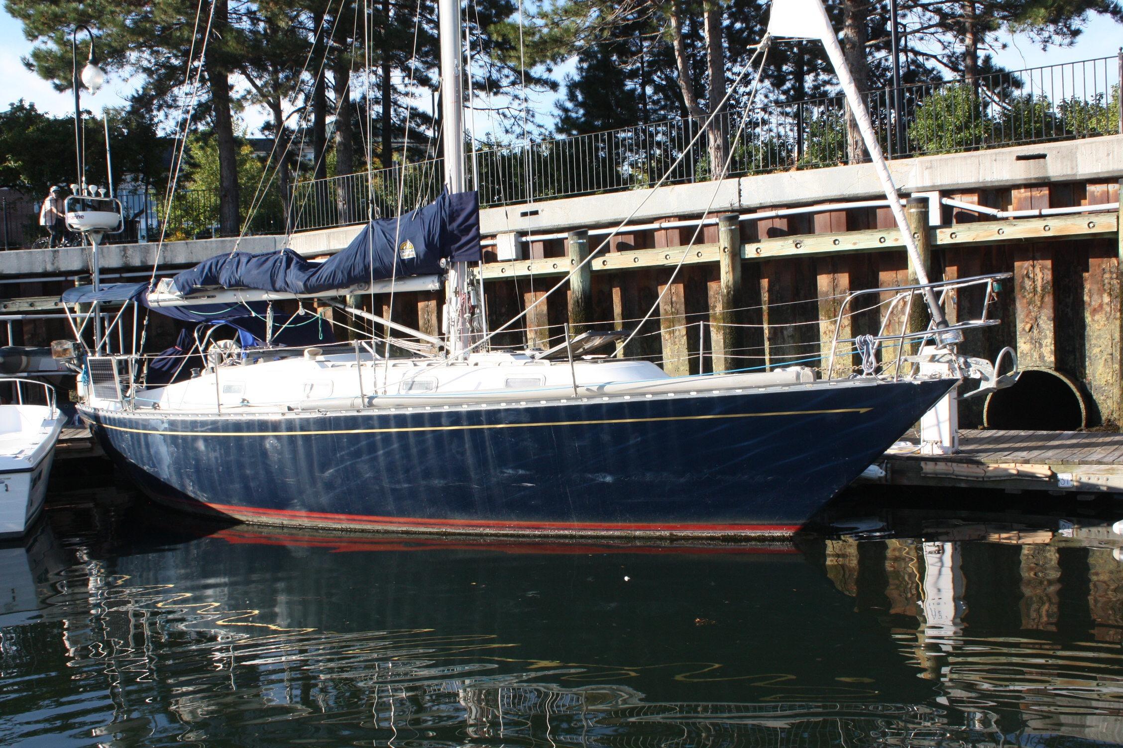 1976 Tartan 38 sailboat docked in a marina, surrounded by trees and calm water.