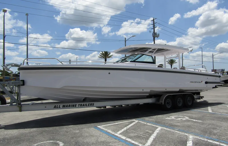  Yacht Photos Pics 2024 Axopar 37 Sun Top boat on a trailer under a cloudy sky.