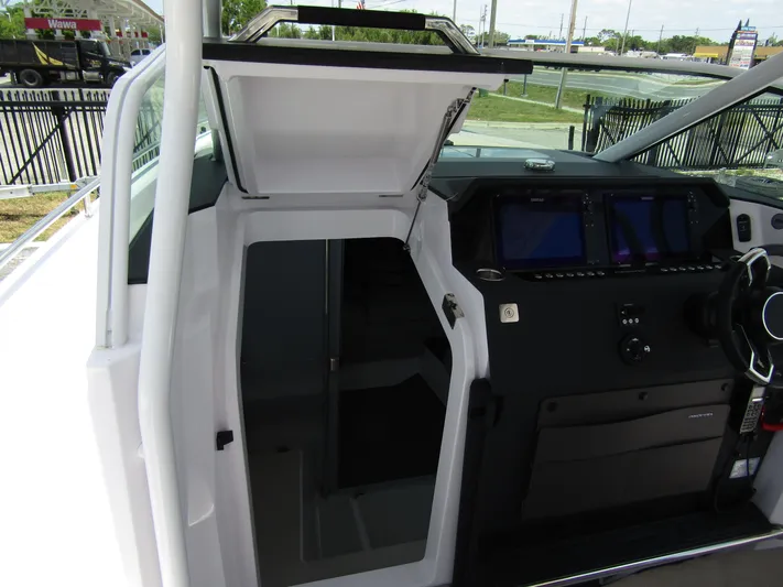  Yacht Photos Pics 2024 Axopar 37 Sun Top helm with open cabin door and modern navigation displays.