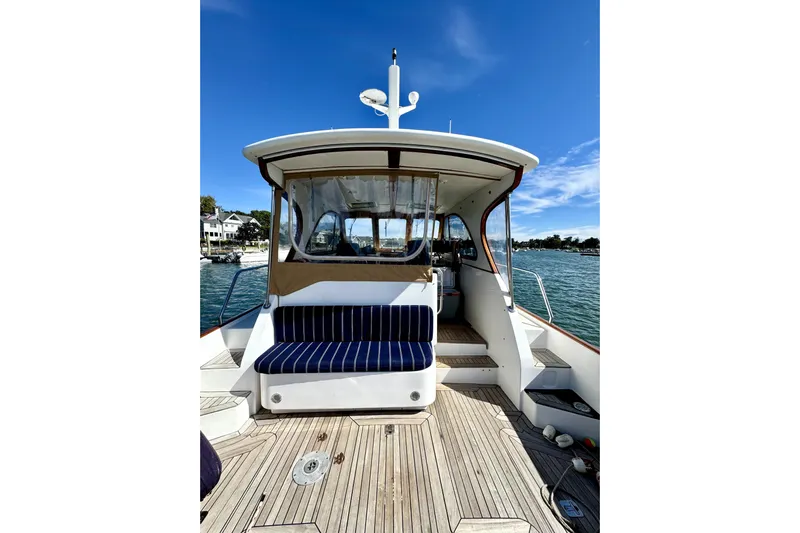 Belle Yacht Photos Pics 2007 Legacy Yachts 34 Sport Express, rear deck view with striped seating, on calm water.