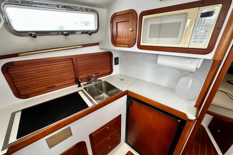 Belle Yacht Photos Pics 2007 Legacy Yachts 34 Sport Express galley with sink, stove, microwave, and wooden cabinetry.