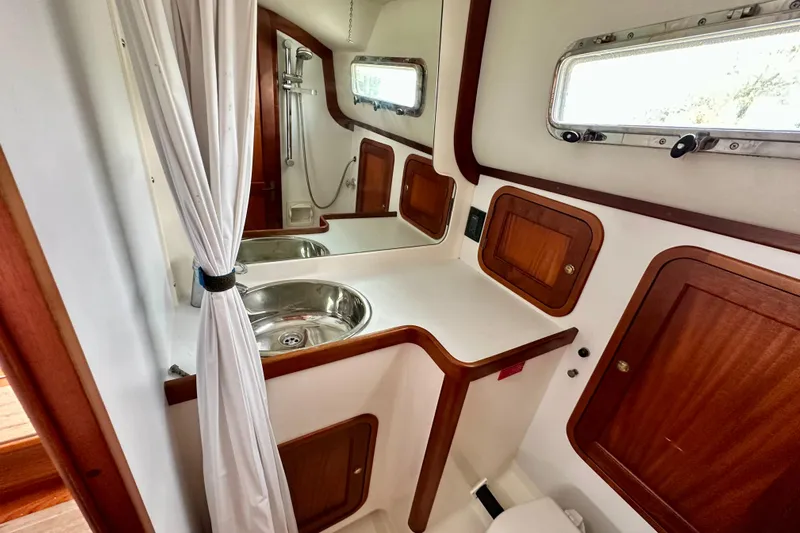 Belle Yacht Photos Pics 2007 Legacy Yachts 34 Sport Express bathroom with sink, shower, and wooden cabinetry.
