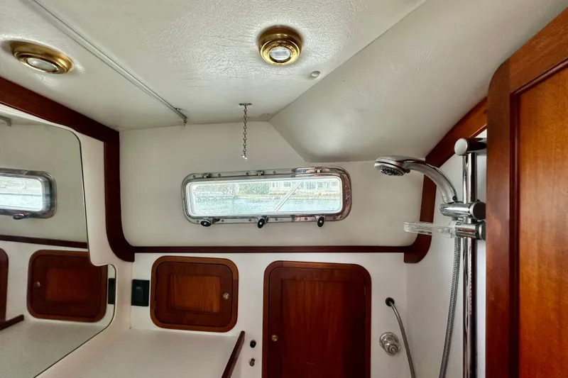 Belle Yacht Photos Pics 2007 Legacy Yachts 34 Sport Express bathroom with shower, wooden cabinets, and porthole window.