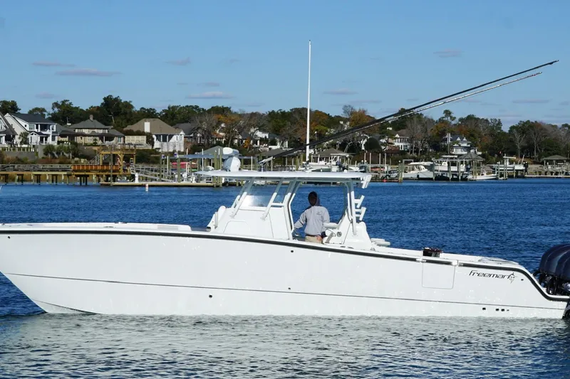  Yacht Photos Pics 2024 Freeman 38 boat cruising on a calm waterfront with houses in the background.