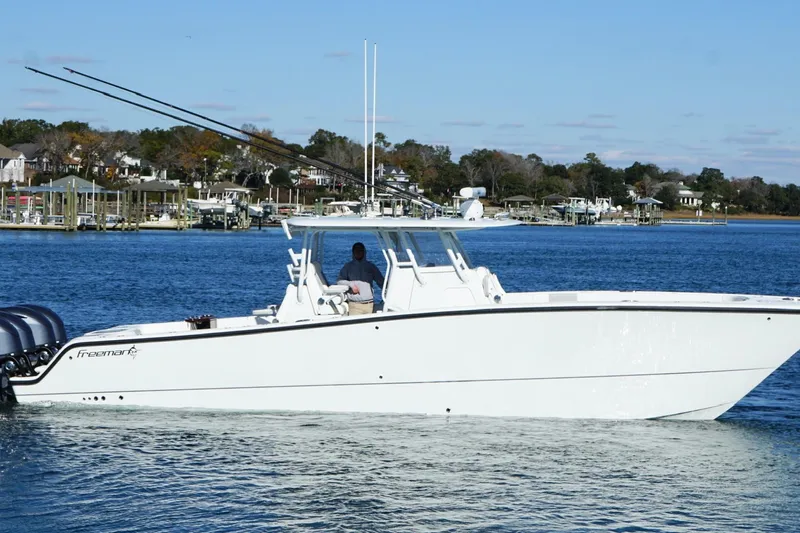  Yacht Photos Pics 2024 Freeman 38 boat cruising on a calm lake with scenic shoreline background.