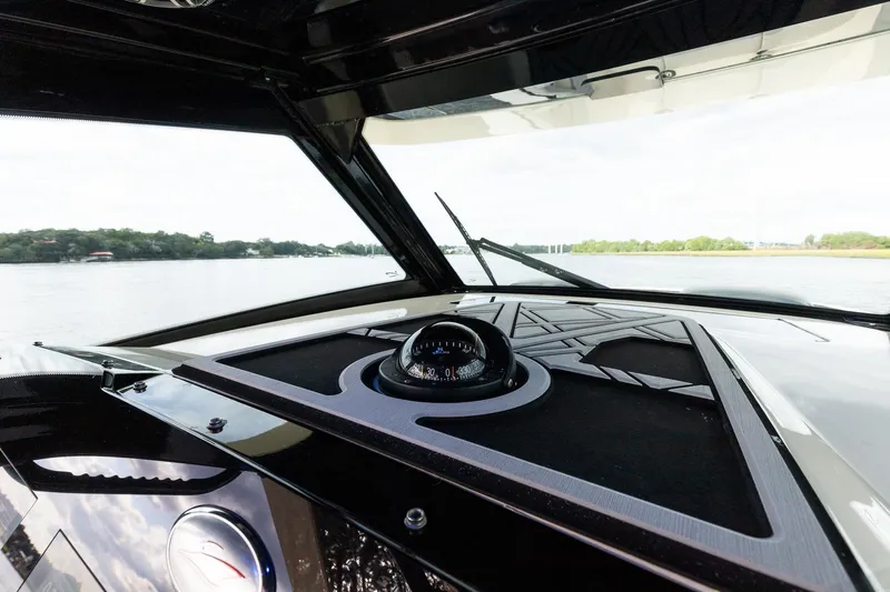 Your Next Boat! Yacht Photos Pics 2024 Scout 377 LXF boat dashboard with compass, overlooking serene water and lush shoreline.