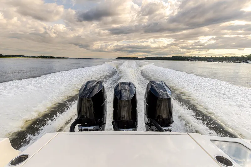Your Next Boat! Yacht Photos Pics 2024 Scout 377 LXF boat with triple engines cruising on a scenic waterway.