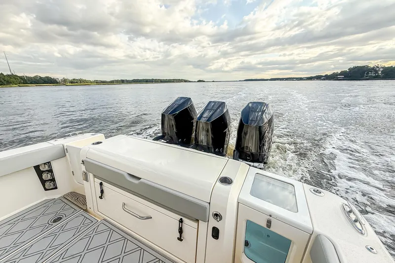 Your Next Boat! Yacht Photos Pics 2024 Scout 377 LXF boat with triple outboard engines cruising on a calm lake.