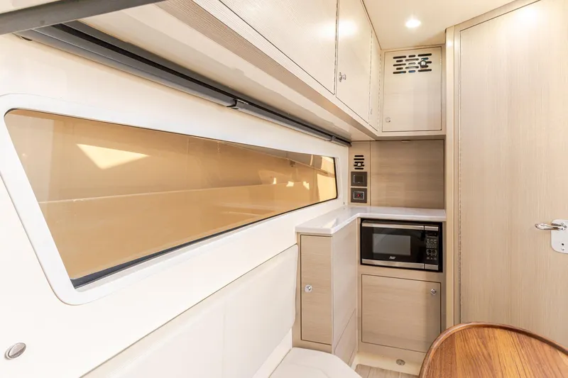Your Next Boat! Yacht Photos Pics 2024 Scout 377 LXF interior with modern kitchenette, featuring microwave and sleek cabinetry.