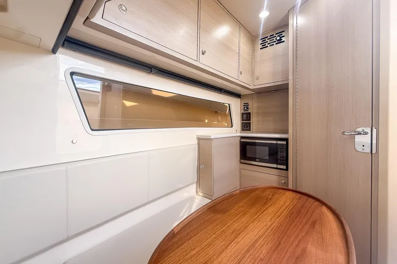 Your Next Boat! Yacht Photos Pics 2024 Scout 377 LXF interior with modern cabinetry, microwave, and wooden table.