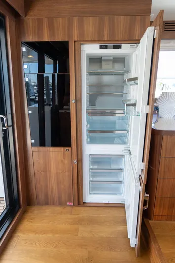 New 2024 Sirena 58 Yacht Photos Pics 2024 Sirena 58 Flybridge yacht interior with open refrigerator, wooden flooring, and modern design.