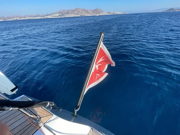 Touché Yacht Photos Pics Windseeker Raised Pilot Saloon 2010 yacht with flag, sailing in clear blue waters.