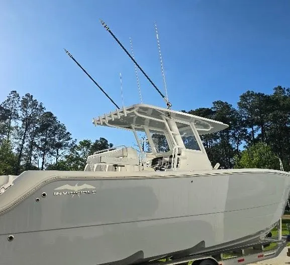 Yacht Photos Pics 2022 Invincible 33 Catamaran boat with fishing rods, parked outdoors under clear blue sky.