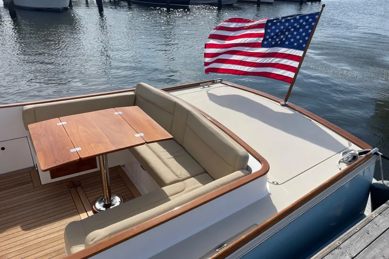 Sea Glass Yacht Photos Pics 2015 CH Marine Shelter Island Runabout with American flag, wooden table, and cushioned seating.