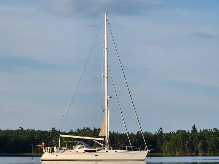 Cinchona Yacht Photos Pics Sailing yacht Outbound 52, 2020 model, anchored on calm water with forested background.