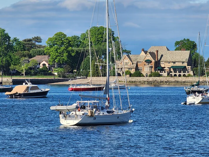 Cinchona Yacht Photos Pics Sailboats on a serene lake with a grand house and lush greenery in the background.