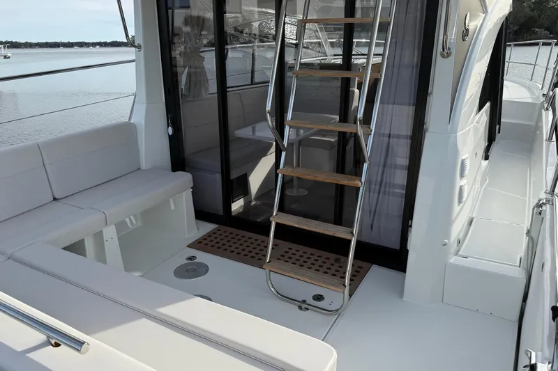 Yacht Photos Pics 2026 Beneteau Antares 11 Fly yacht interior with seating and ladder, docked by the water.