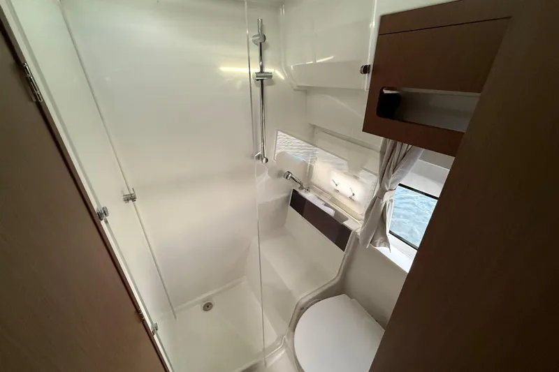 Yacht Photos Pics 2026 Beneteau Antares 11 Fly bathroom with shower, toilet, and window.