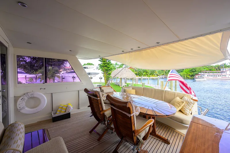 Forever Young Yacht Photos Pics Luxurious 1991 Hatteras 78 CMY yacht deck with seating, table, and scenic waterfront view.