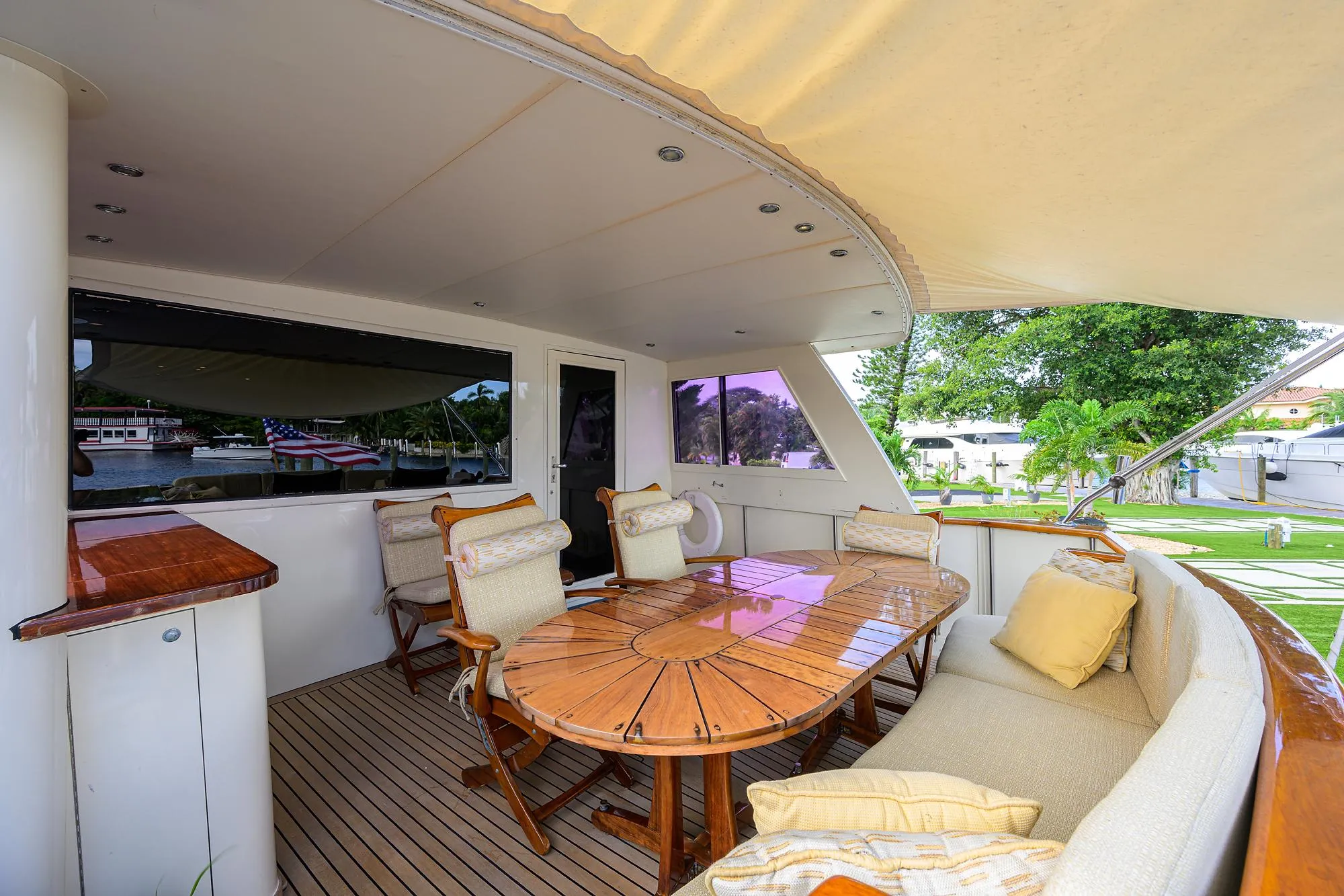 Outdoor seating area on a 1991 Hatteras 78 CMY yacht with wooden table and cushioned chairs.