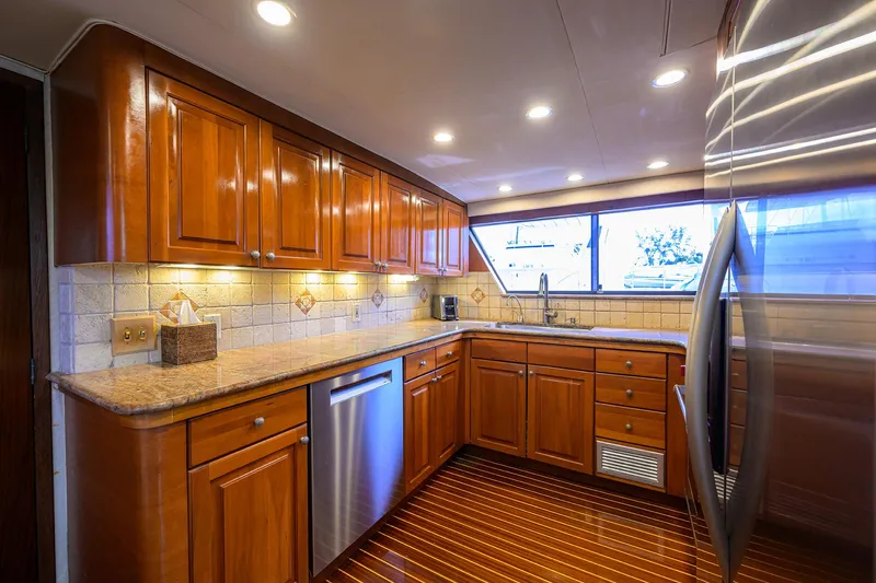 Forever Young Yacht Photos Pics Luxurious kitchen interior of 1991 Hatteras 78 CMY yacht with wooden cabinets and modern appliances.
