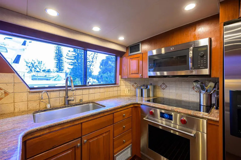 Forever Young Yacht Photos Pics Luxurious kitchen interior of 1991 Hatteras 78 CMY yacht with modern appliances and wood cabinetry.