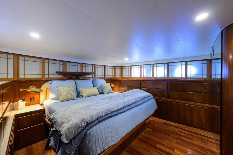 Forever Young Yacht Photos Pics Luxurious bedroom interior on 1991 Hatteras 78 CMY yacht with wood paneling and cozy bedding.